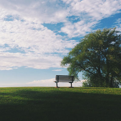Bench on hilltop with clouds in sky